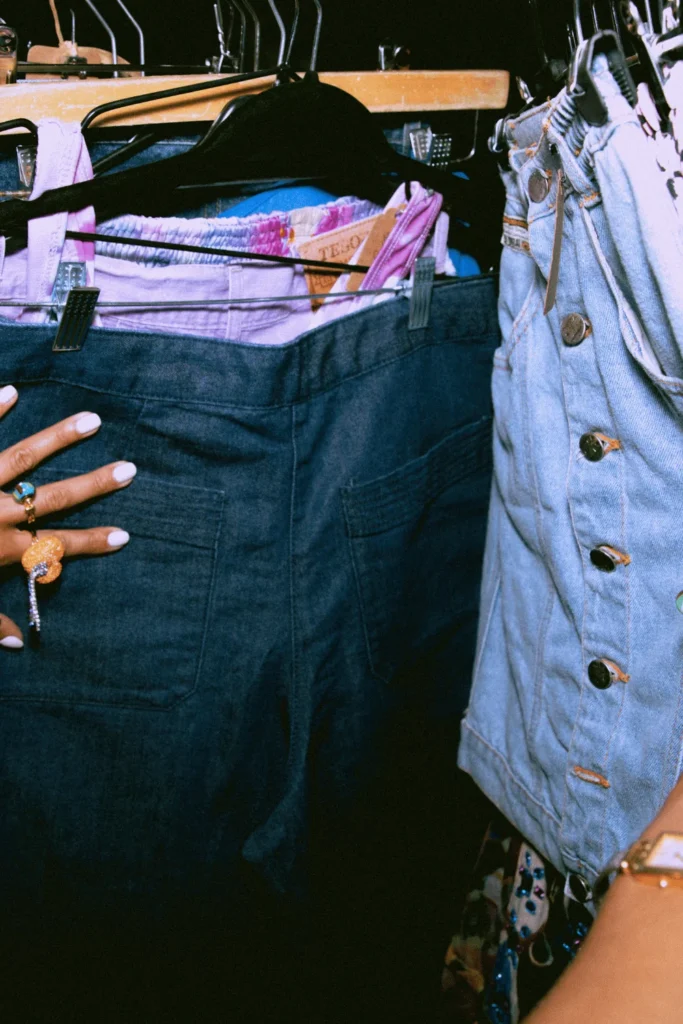 image of a female_s hands sifting through thrifted clothing racks