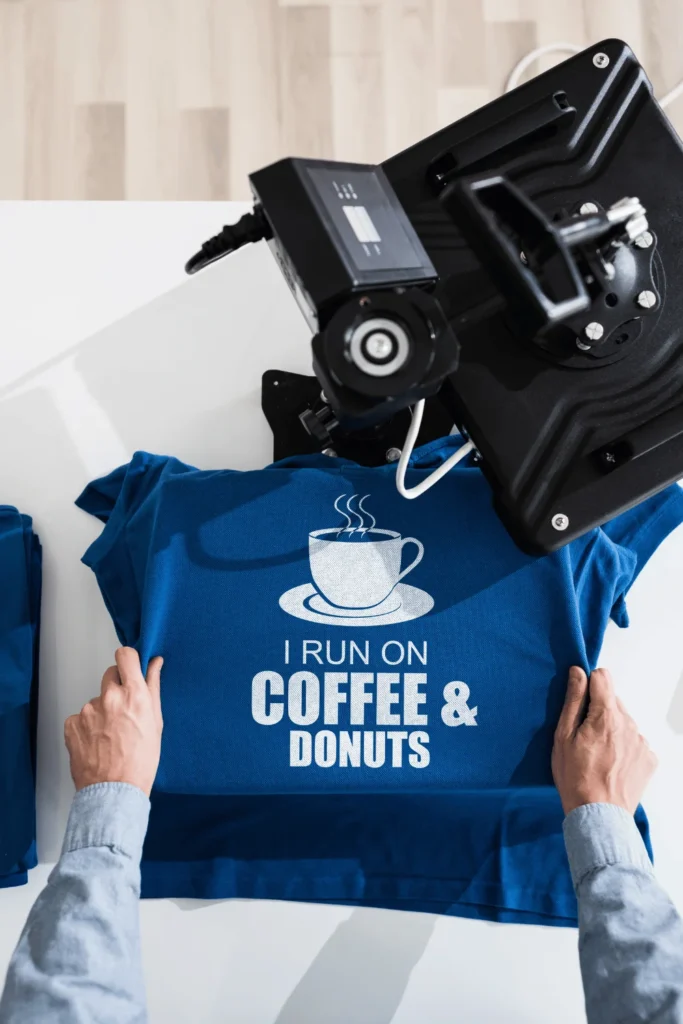 image of a person making a blue shirt on a sublimation printer that says i run on coffee and donuts